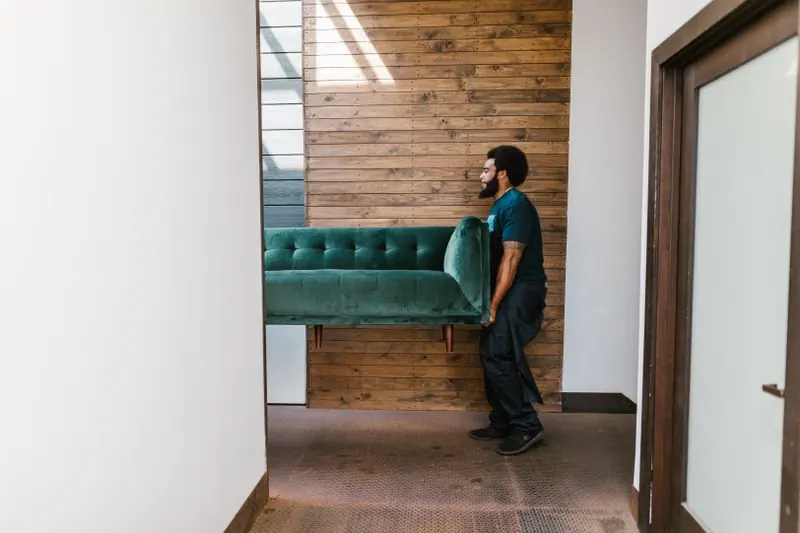 A mover carrying a sofa into a room